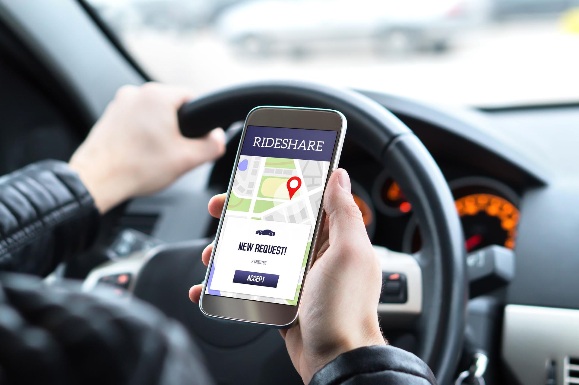 Ride share driver in car using the rideshare app in mobile phone. New taxi ride request from customer in smartphone application.